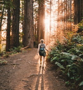 a woman walking down a path in the woods