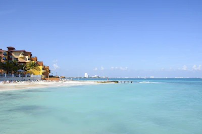 Cozy seaside vacation home with turquoise waters in the background under a clear sky.