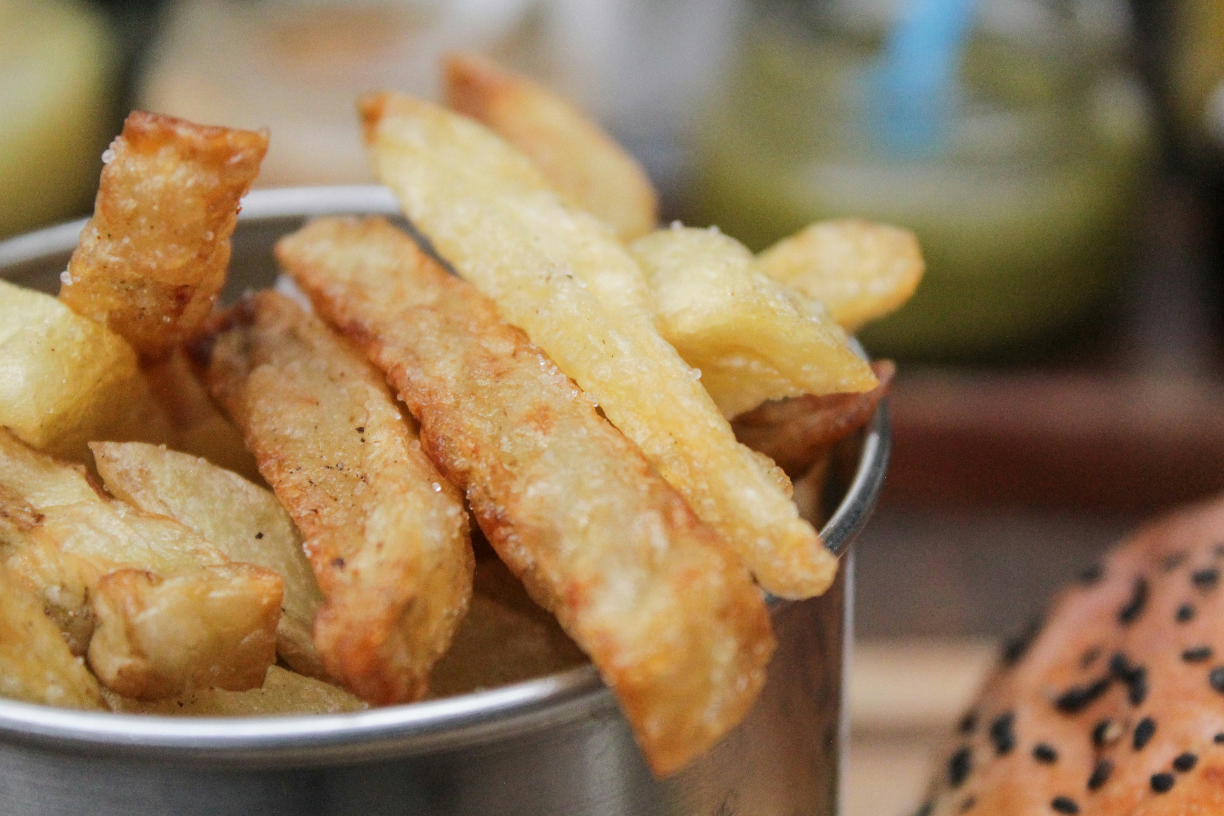 Golden fries in dark bowl with salt, moody dim background close up