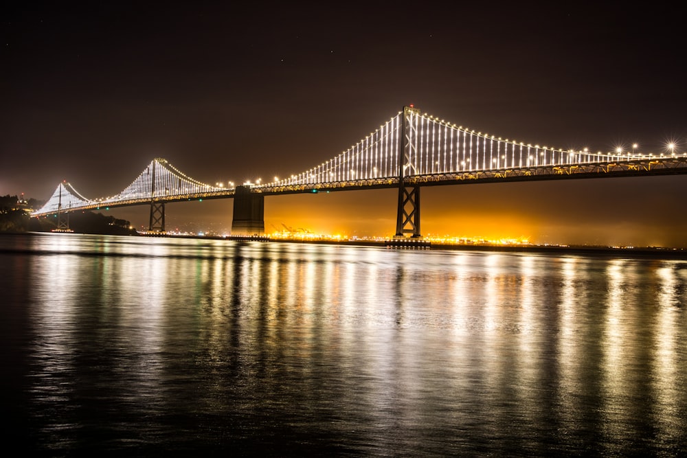 Puente iluminado sobre el cuerpo de agua durante la noche