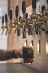 person holding beer mug under keg tap