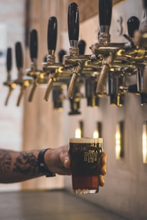 person holding beer mug under keg tap