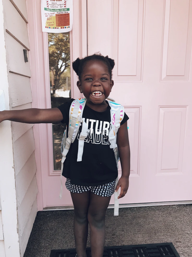 Young child waving goodbye to parent at daycare entrance