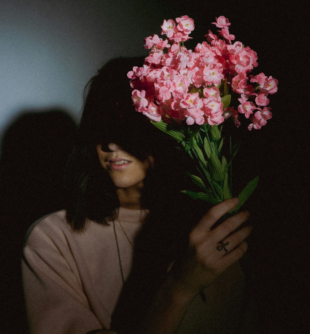 mujer sosteniendo decoraciones de flores rosas falsas