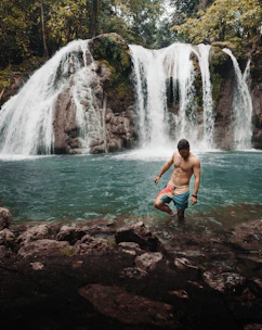 A moody shot of a fighter stepping into a cold plunge pool surrounded by lush jungle foliage at dusk.