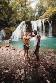 two man standing in front of the waterfalls during daytime