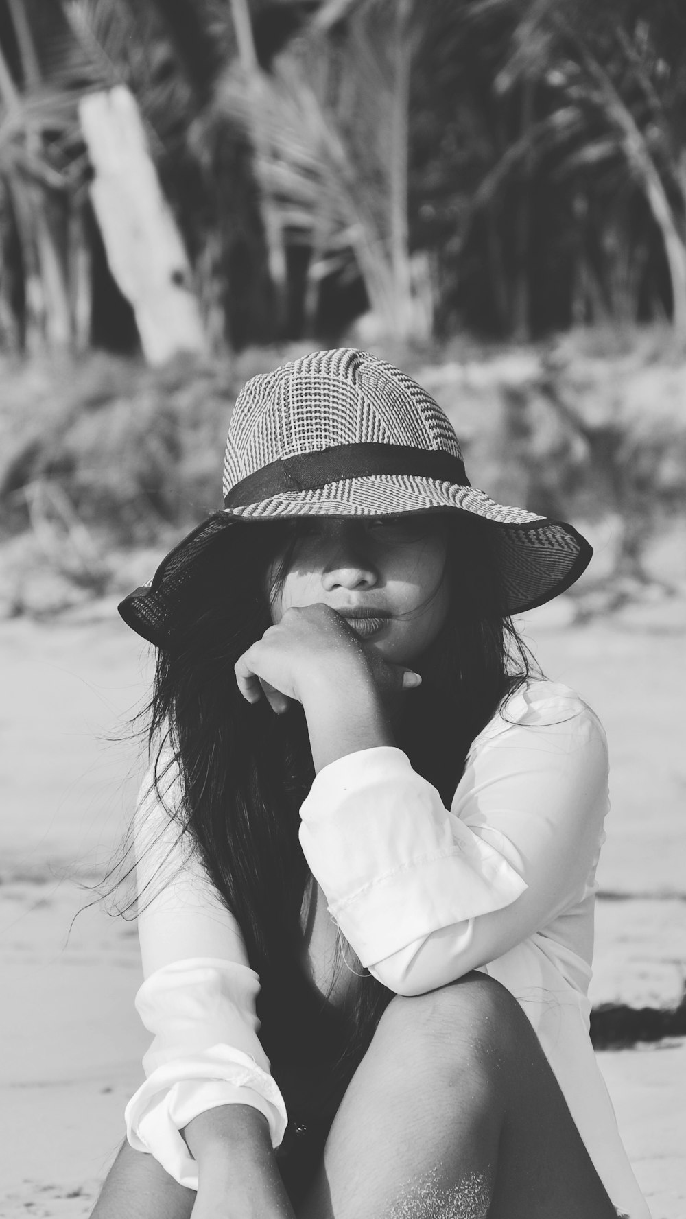 grayscale photography of woman sitting near shore