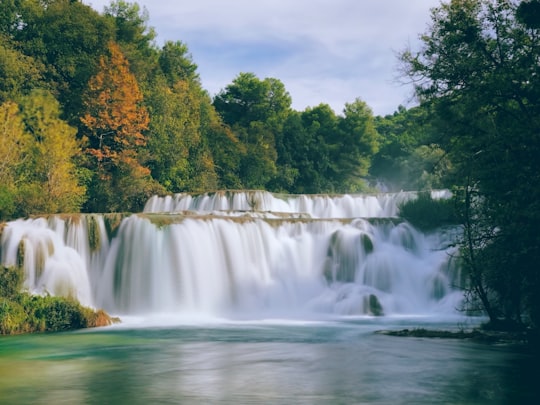 waterfalls with trees under cloudy sky in Krka National Park Croatia