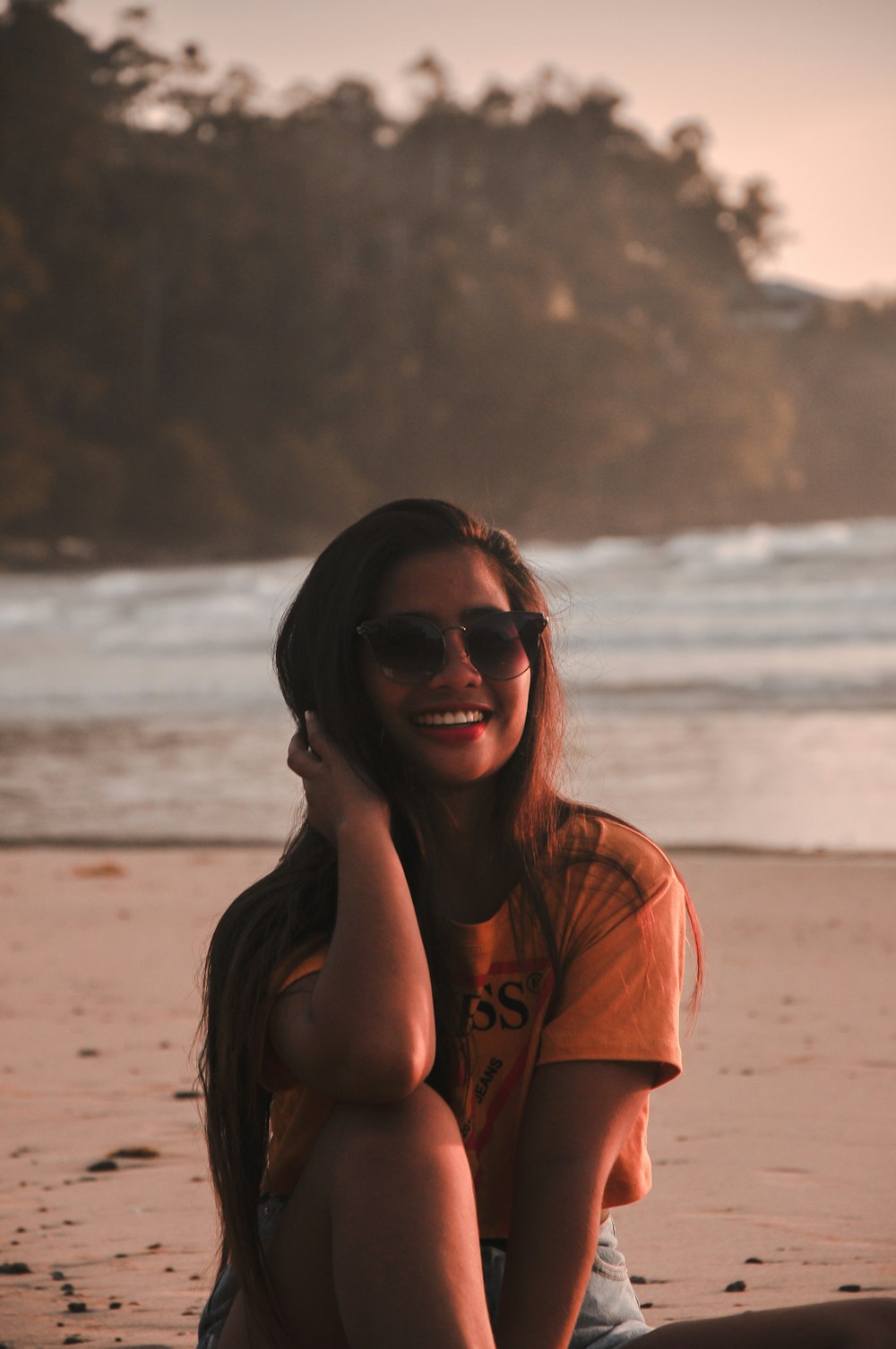 donna che si siede sulla sabbia mentre sorride