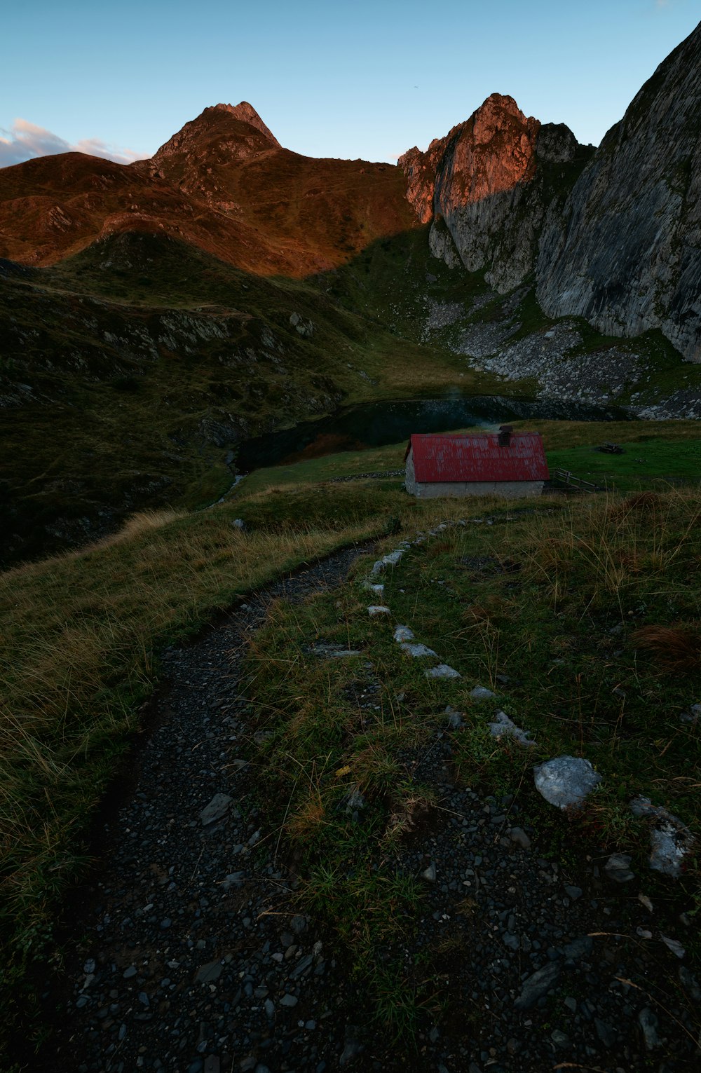 white and red house surrounded by trees and hill under white clouds and blue sky