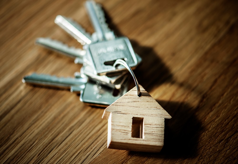 selective focus photography of four silver keys with brown house keychain on brown surface buying a home ten steps when buying a home