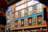 Vibrant and ornate wall featuring colorful murals with spiritual and religious themes, incorporating figures and intricate patterns in a temple-like setting.