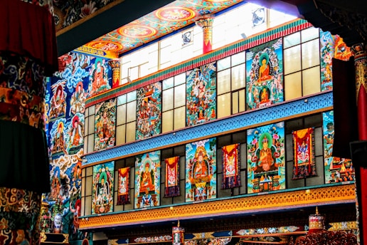 Vibrant and ornate wall featuring colorful murals with spiritual and religious themes, incorporating figures and intricate patterns in a temple-like setting.
