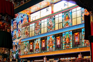 Vibrant and ornate wall featuring colorful murals with spiritual and religious themes, incorporating figures and intricate patterns in a temple-like setting.