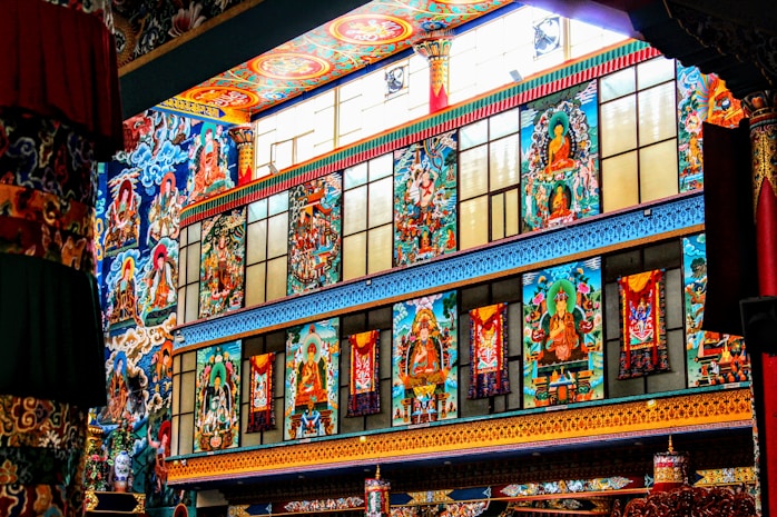 Vibrant and ornate wall featuring colorful murals with spiritual and religious themes, incorporating figures and intricate patterns in a temple-like setting.
