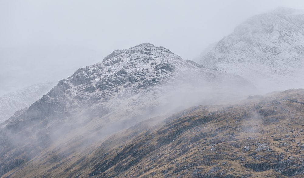 snow filled mountain surrounded by fogs