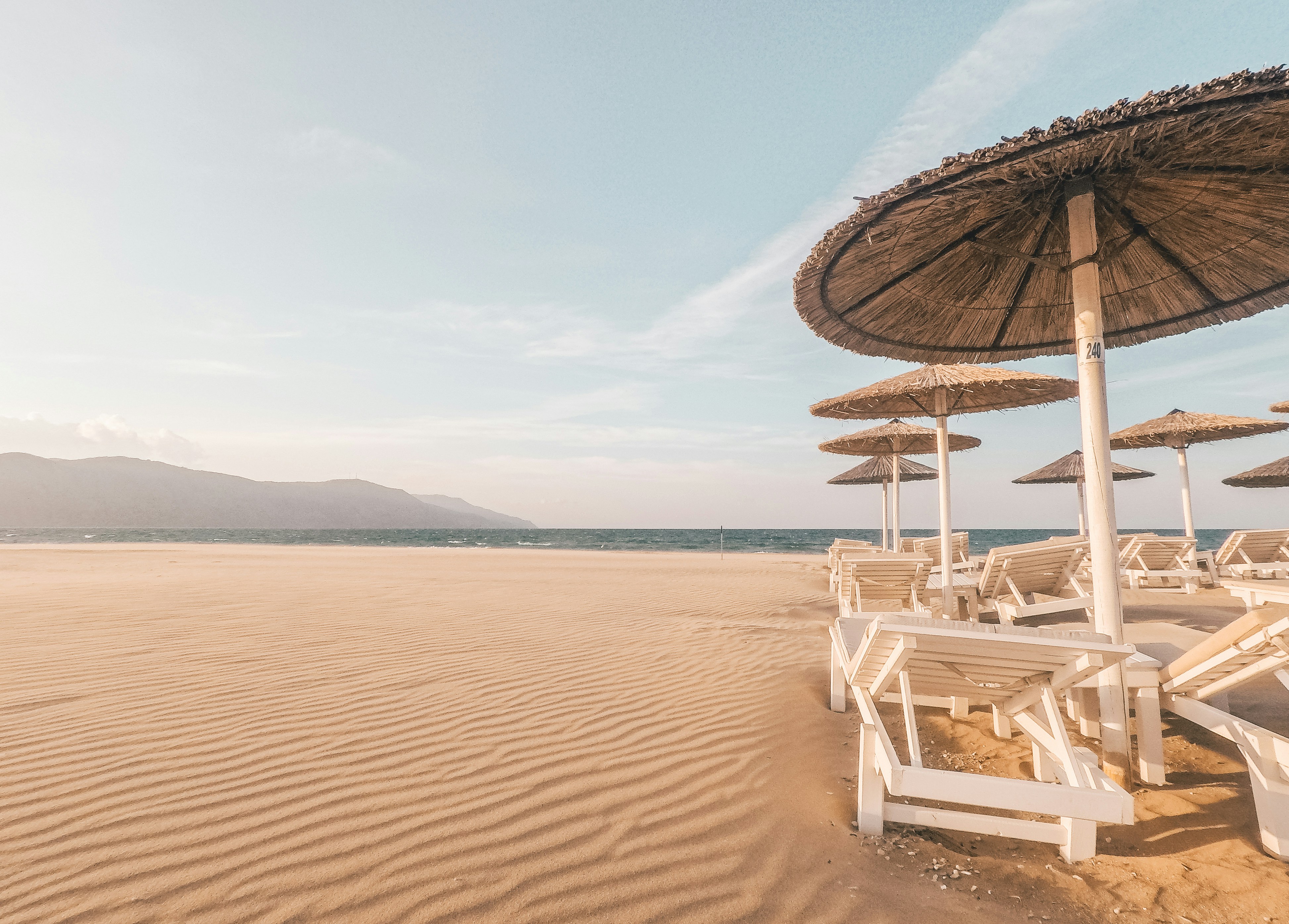 lounge chairs with umbrellas at the beach during day, the calm before the storm