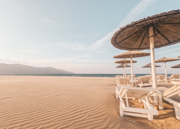 A sunlit beach with a cozy lounge chair and a travel map beside it.