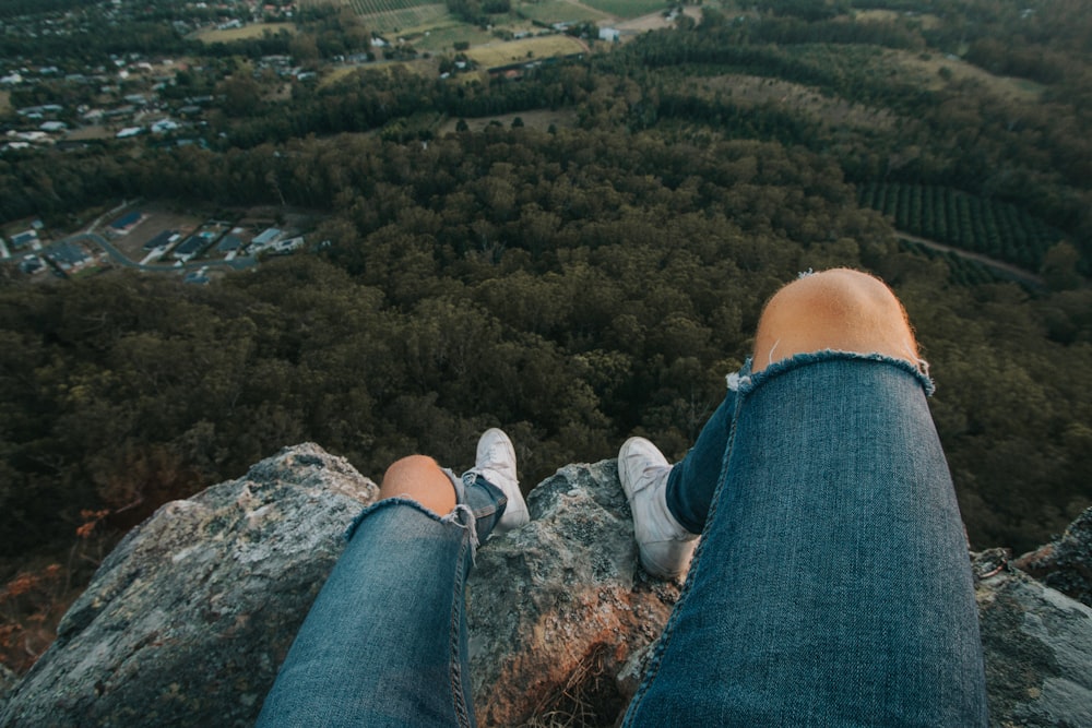 person sitting on cliff taken at daytime