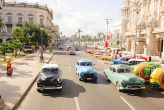 three assorted-colored vintage car on road