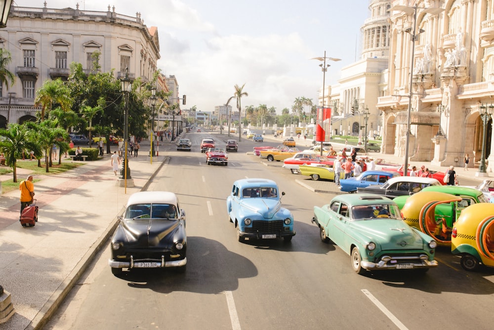 three assorted-colored vintage car on road