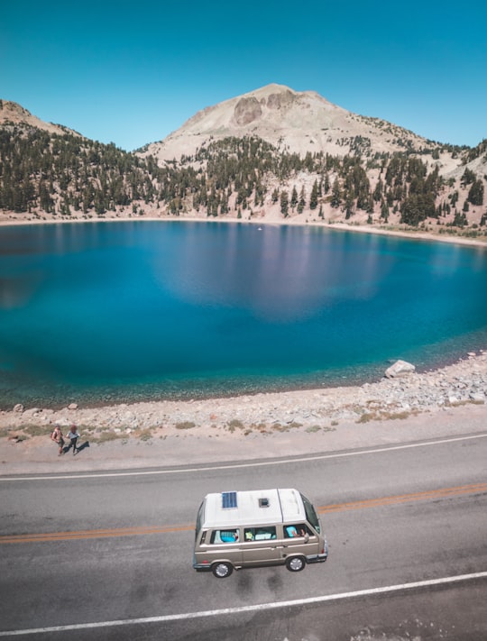 vehicle travelling on road near lake and mountain in Lassen Volcanic National Park United States
