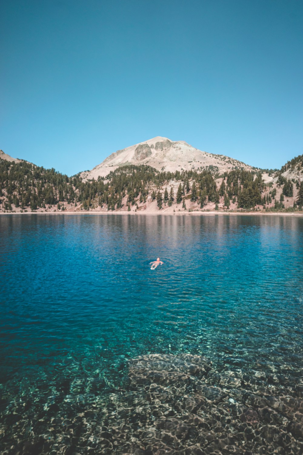 man floating on blue sea surrounded by mountain