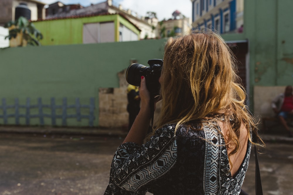 woman holding black DSLR camera during daytime