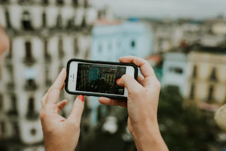 A friendly person holding a smartphone with Medellín cityscape in the background.