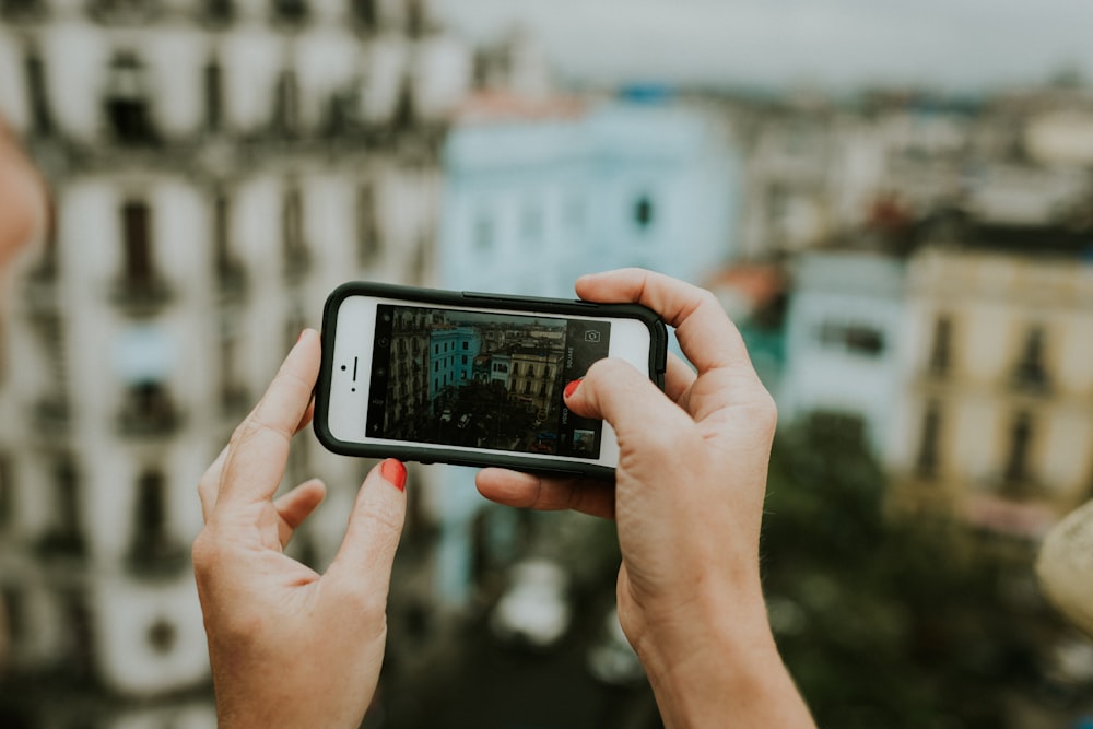 person taking photo of building using iPhone 5s during daytime