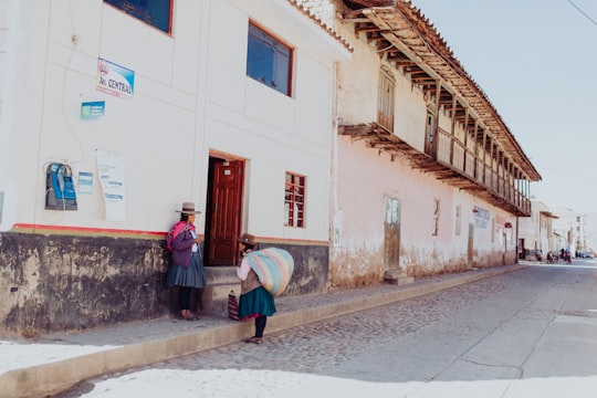 two women talking while standing near building duting daytime in Cusco Peru