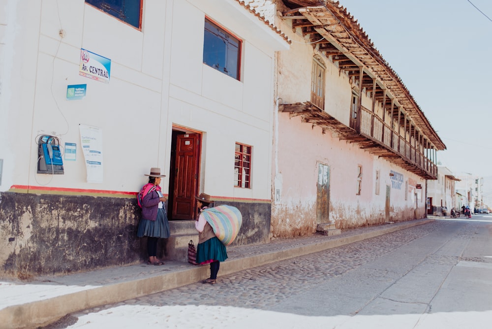 two women talking while standing near building duting daytime