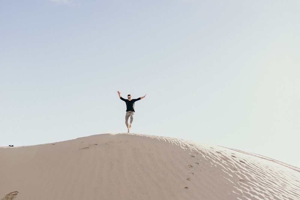 homem pulando na areia marrom durante o dia