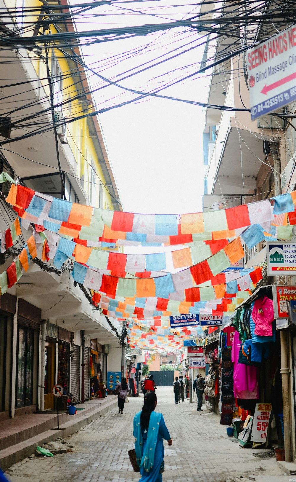 woman walking on alley with buntings during daytime