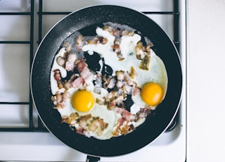 two fried eggs with meat on frying pan