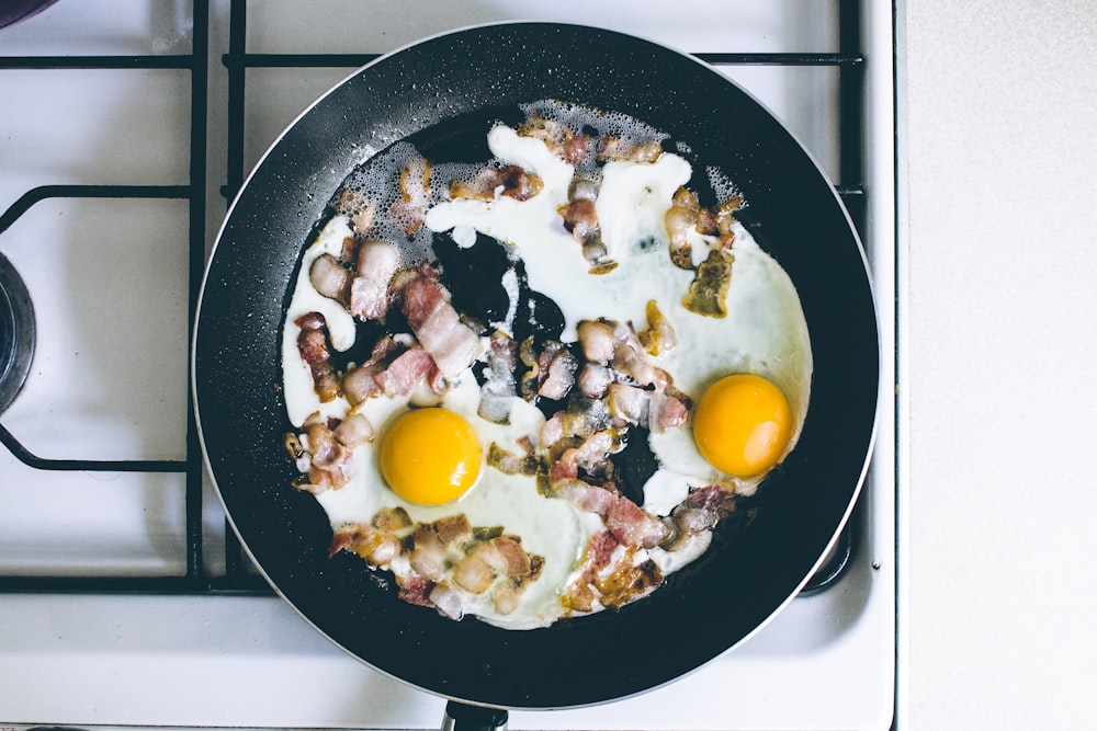two fried eggs with meat on frying pan