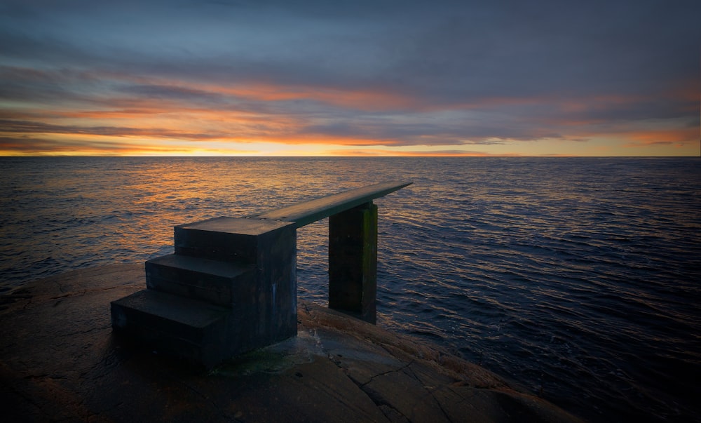 grey stairs on body of water during golden hour