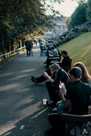 group of people sitting on park beside pathway during daytime