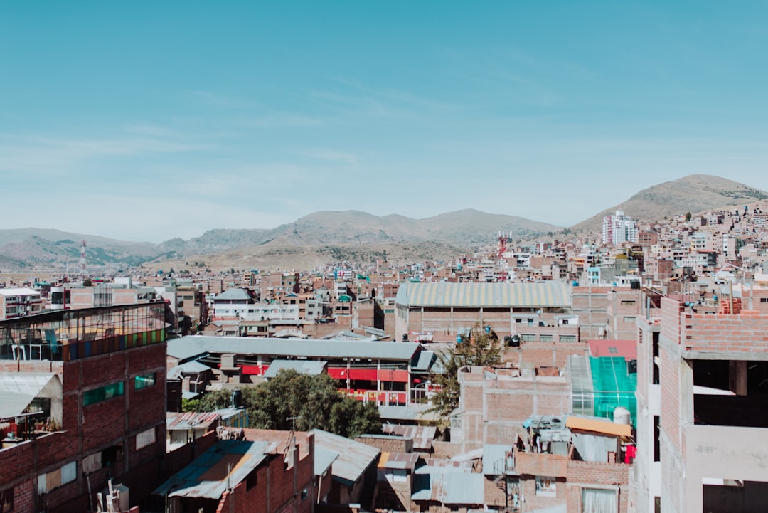 brown concrete houses near brown mountain under blue sky, Puno