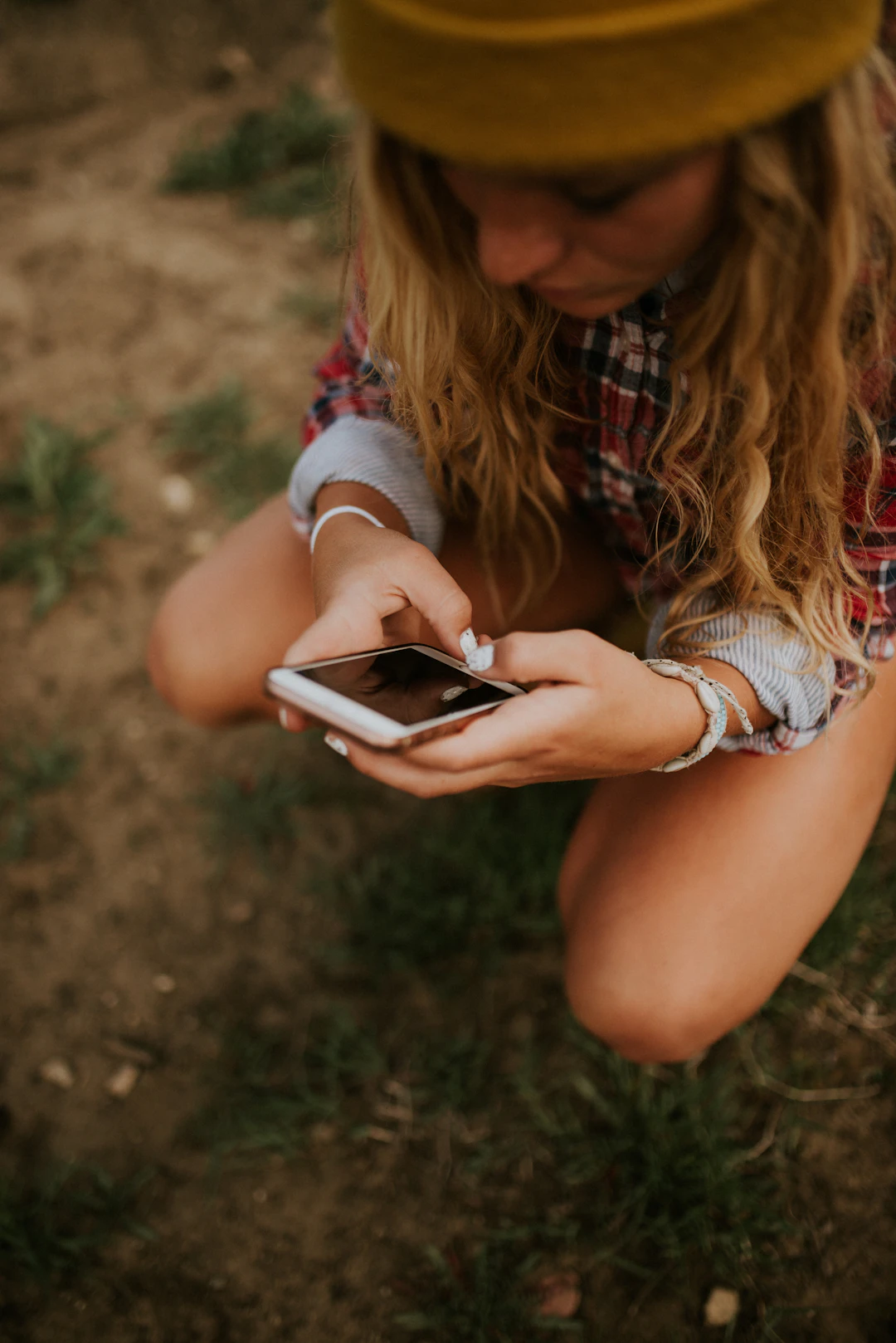Jeune assise dans l'herbe en train de consulter son smartphone