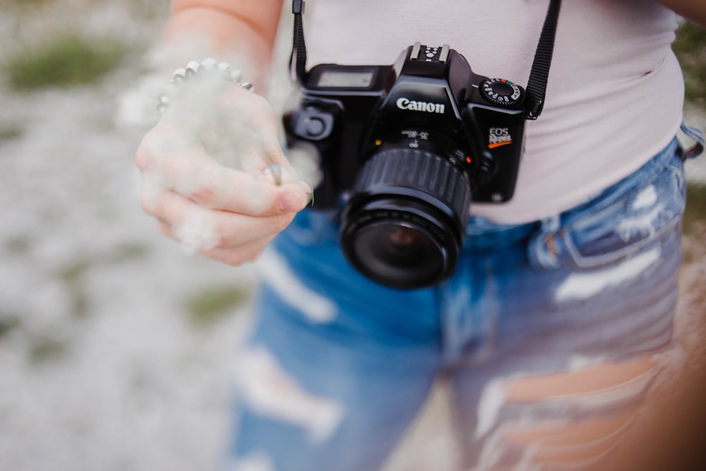 person carrying black Canon DSLR camera