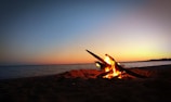 A cozy beach campfire at dusk, soft waves kissing the shore nearby.