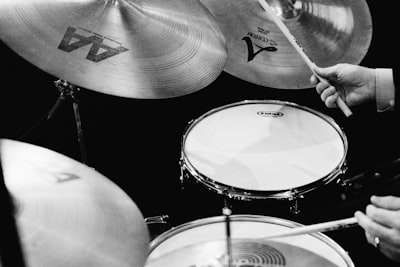grayscale photography of man playing drums drumstick zoom background
