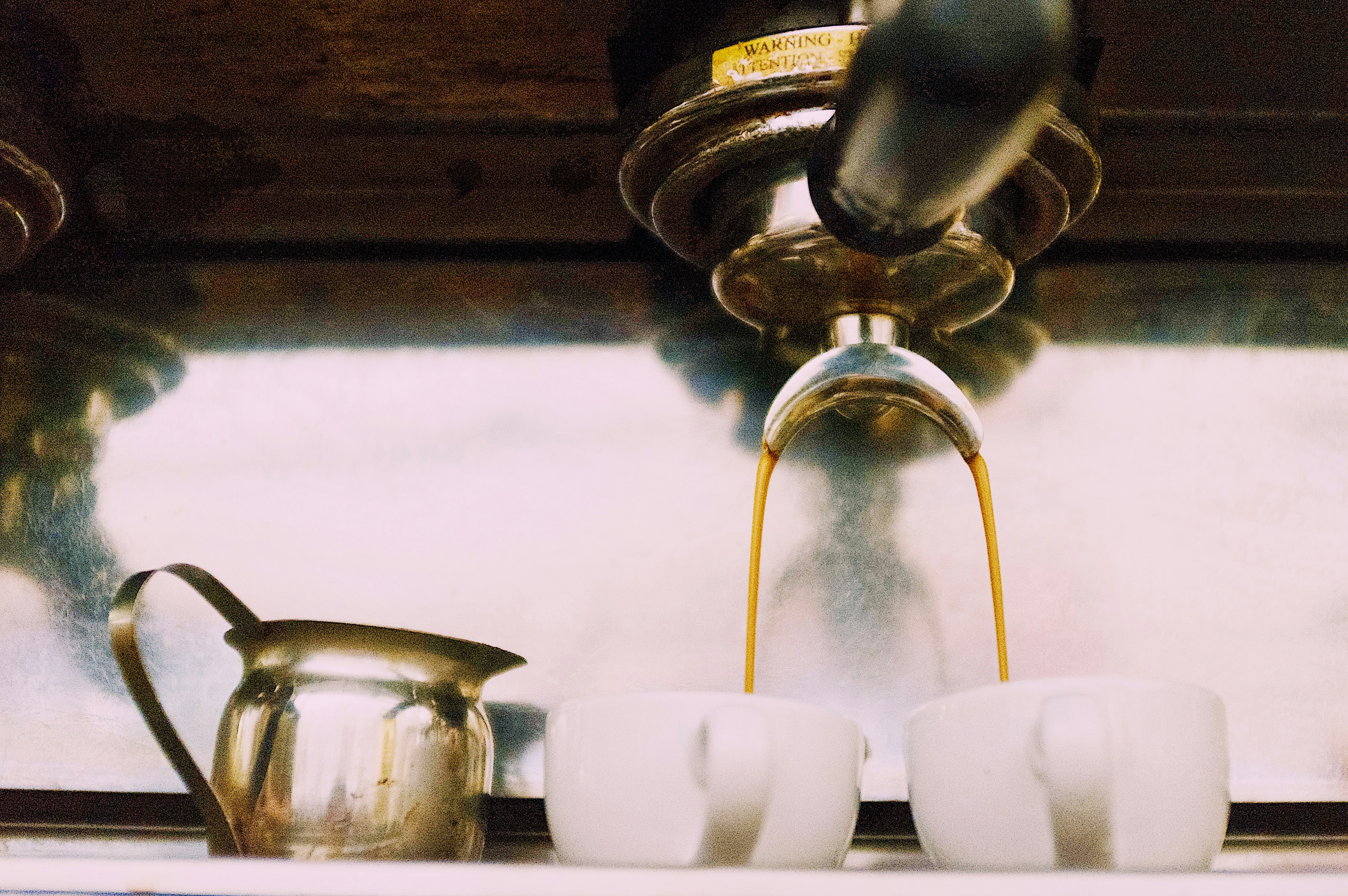 gray and black espresso machine pouring coffee in two white ceramic mugs