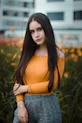 selective focus photo of woman standing in front of bed of yellow petaled flowers