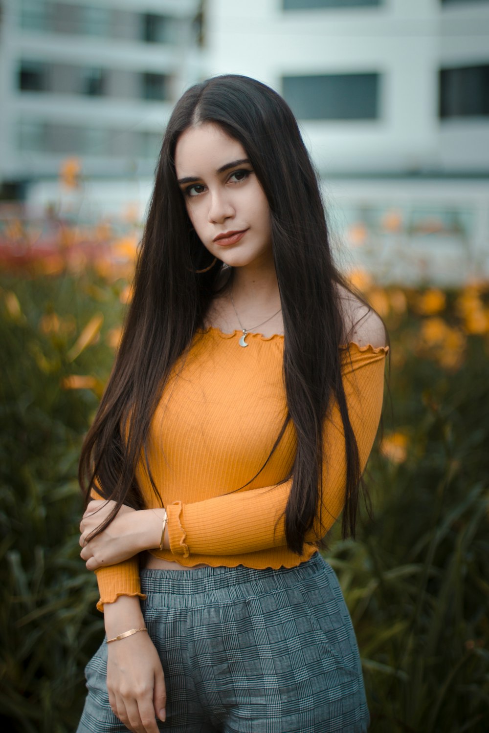 selective focus photo of woman standing in front of bed of yellow petaled flowers