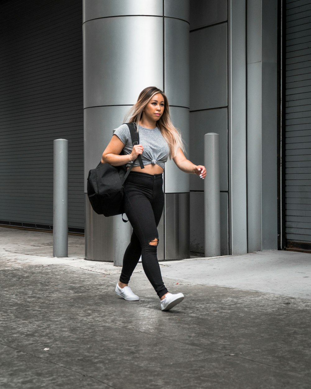 woman walking beside grey building