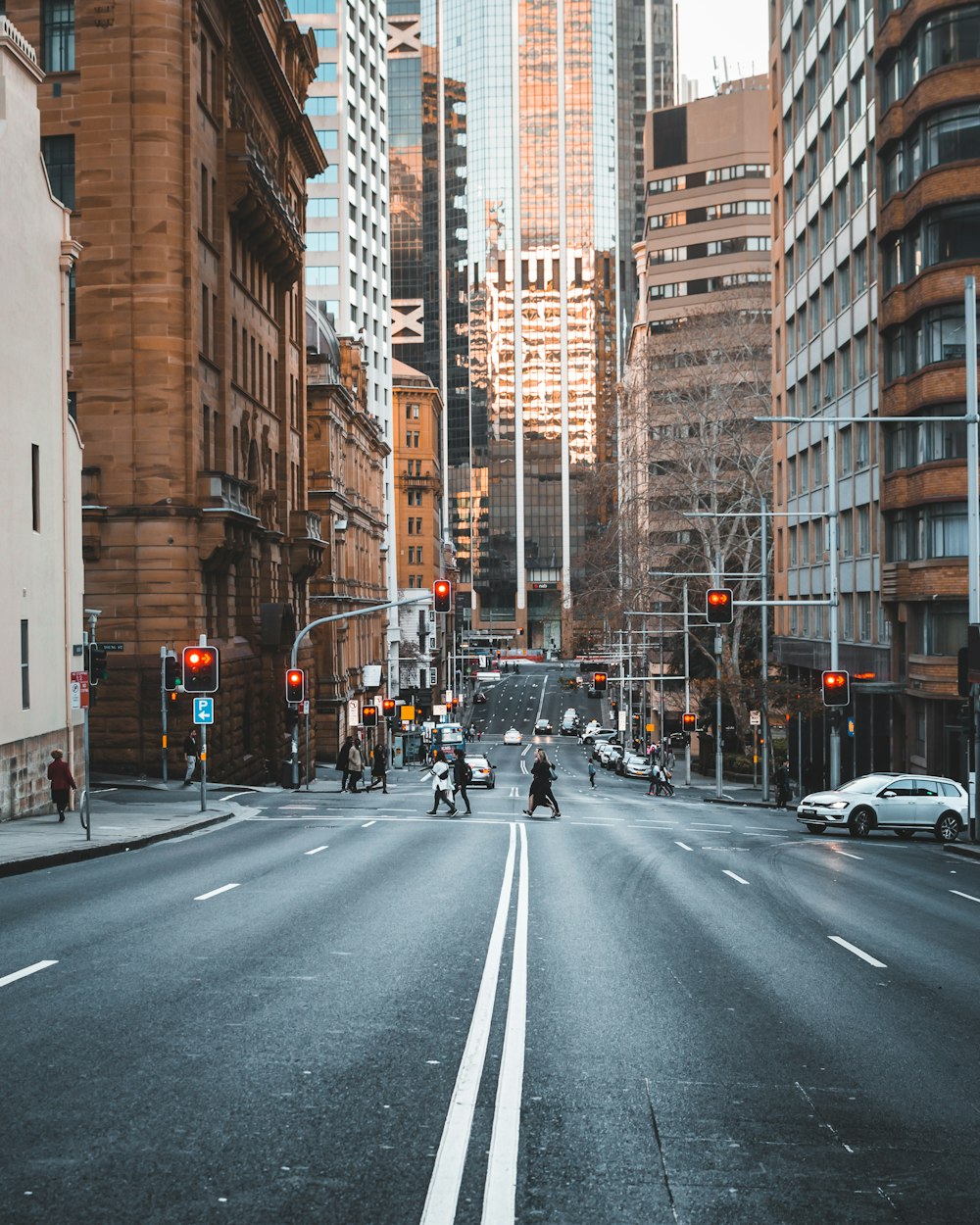 people crossing the street surrounded with high-rise buildings