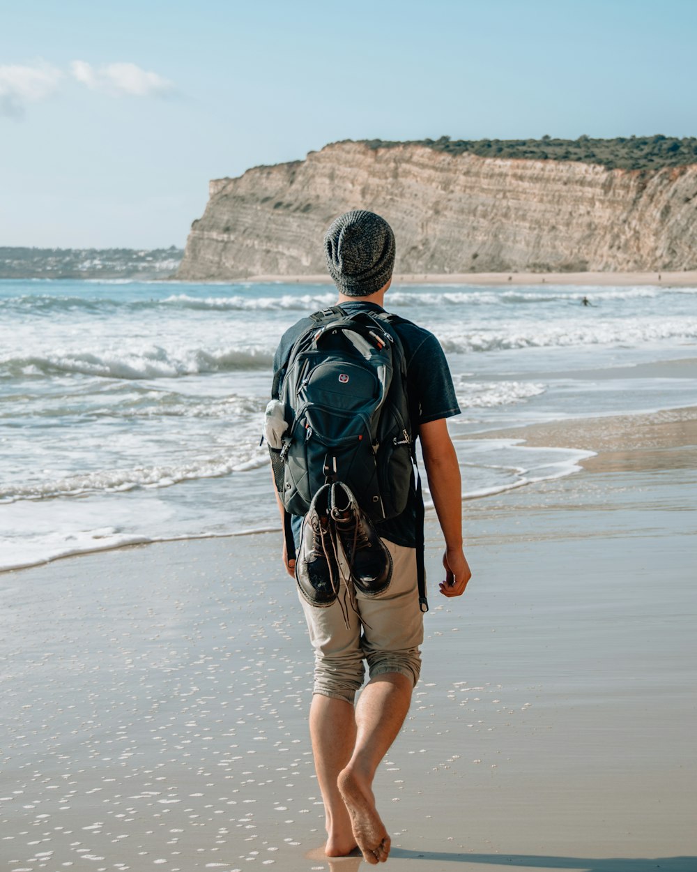 man walking on seashore near cliff
