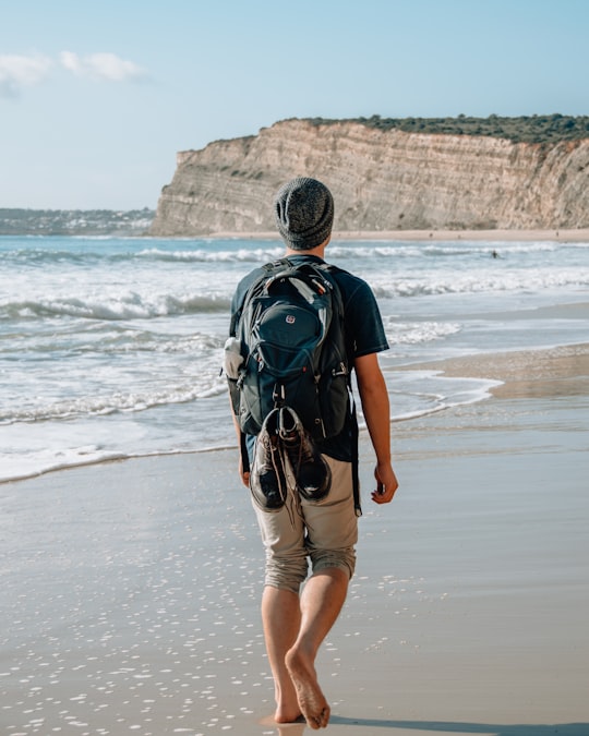 man walking on seashore near cliff in Lagos Portugal